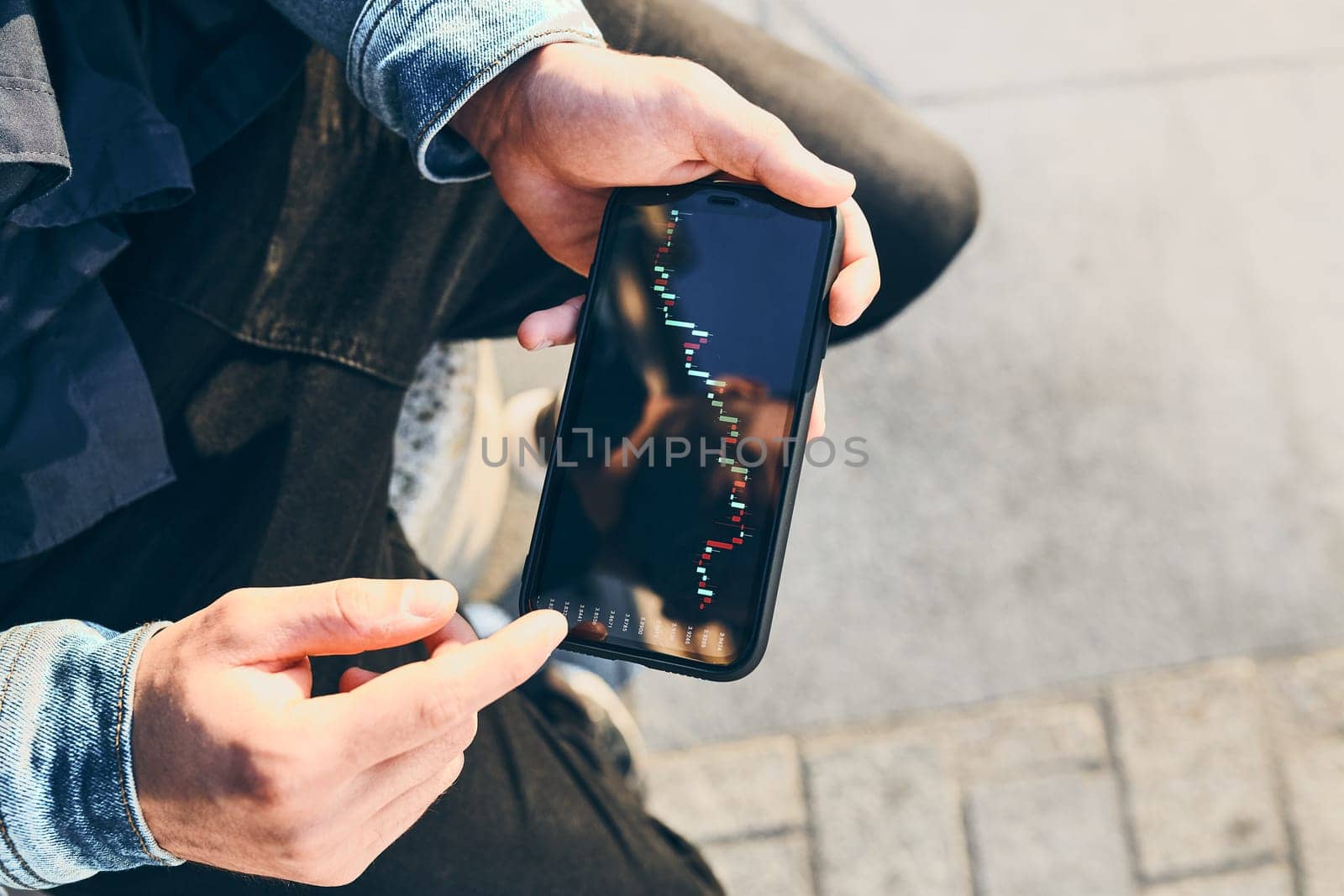 Person investing trading on stock cryptocurrency market using investing application on smartphone. Stock market investment in hand. Trader holding mobile phone looking at candle chart