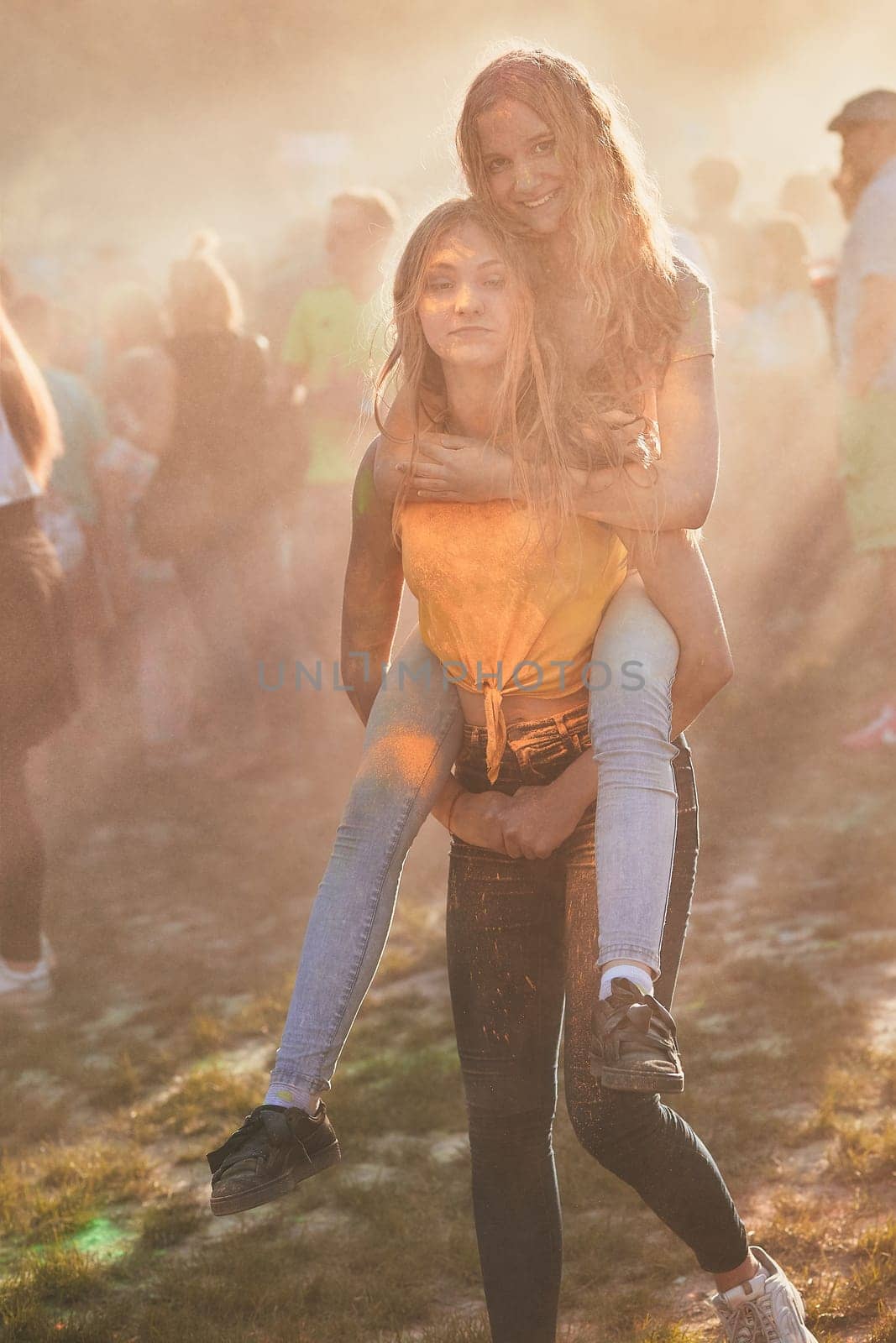 Portrait of happy smiling young girls with colorful paints on faces and clothes. Two friends spending time on holi color festival
