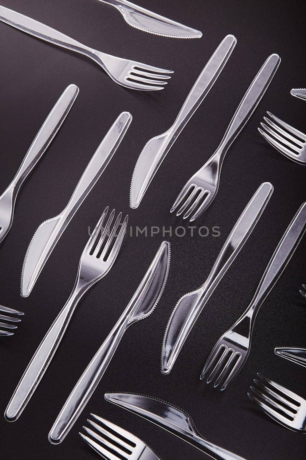 Plastic forks and knives scattered over red background. Collecting plastic waste to recycling. Concept of plastic pollution and too many plastic waste. Copy space at the top