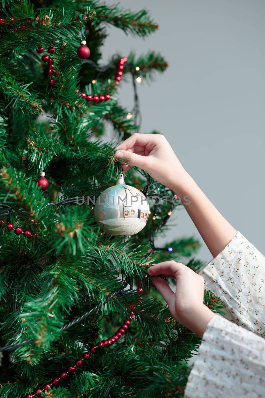 Young girl decorating Christmas tree with hand painted ball at home