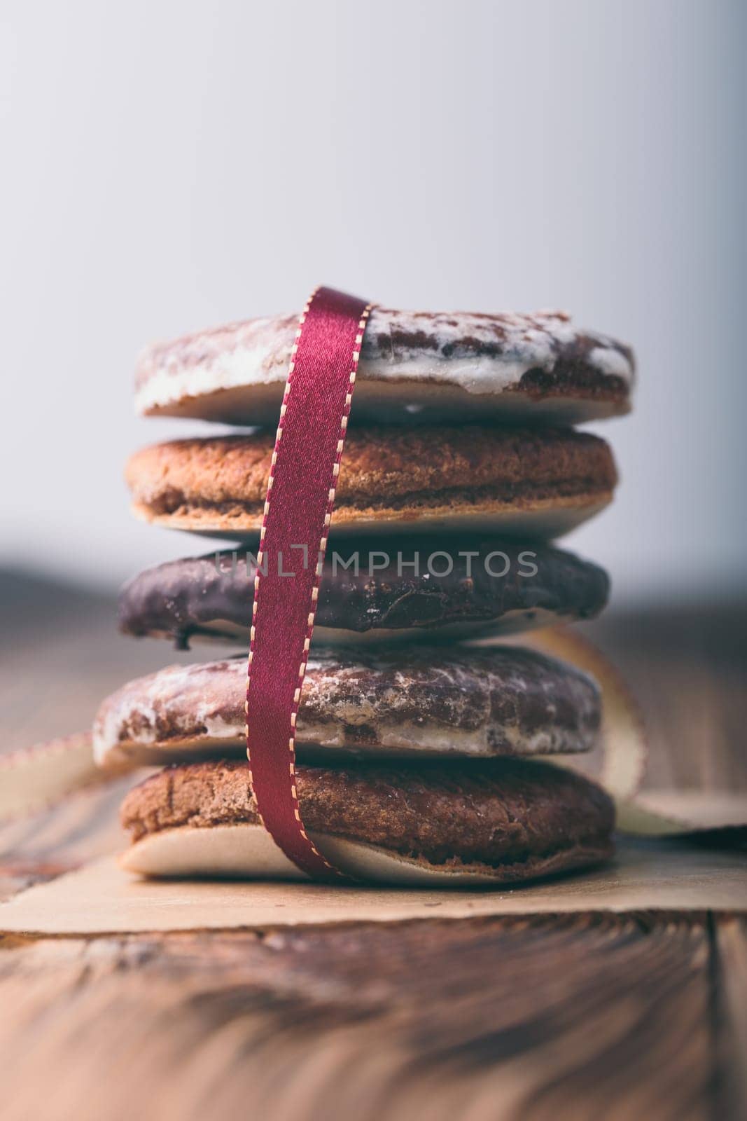 A few gingerbread cookies wrapped in red ribbon Happy Christmas. Plain background. Portrait orientation
