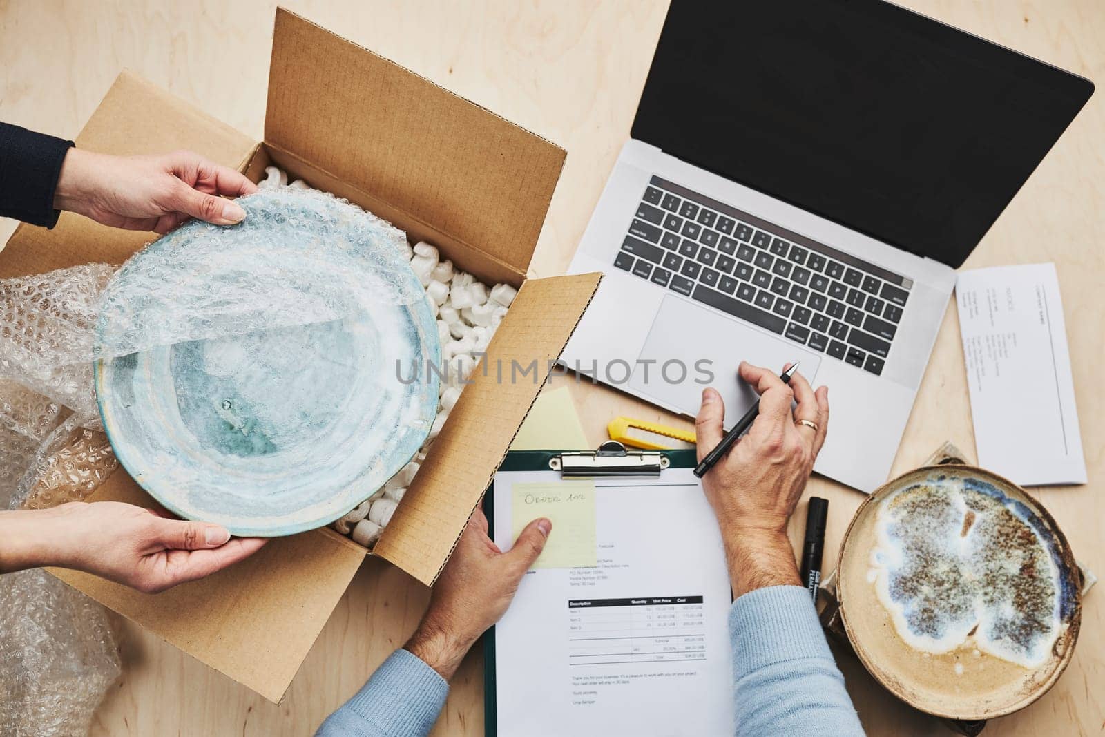 Business owner packing online order to delivery to customer. Preparing parcel box with ceramic plate product from online shop