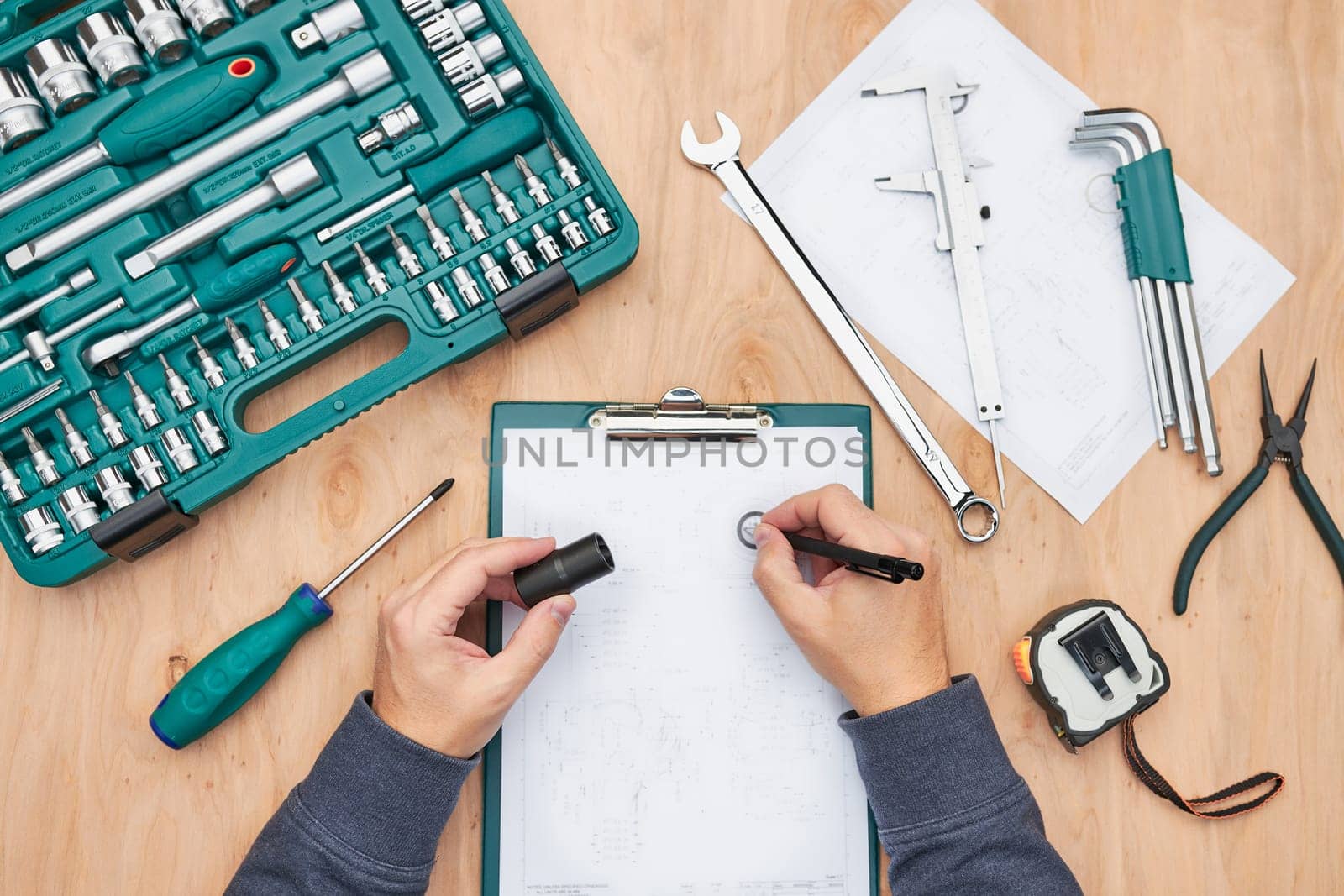 Man working in workshop using many tools. Wrench, spanner, calliper and ratchet with many attachments. Work tools. Universal tool set. Professional equipment
