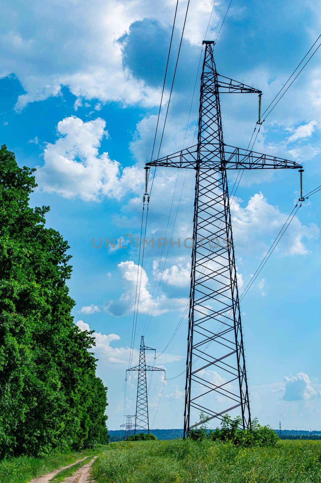 Tower with high-voltage energy transmission wires against the blue sky. High-voltage tower. Electrical wires and fuses. Energy business. Energy industry. Import and export of energy. Blue sky.