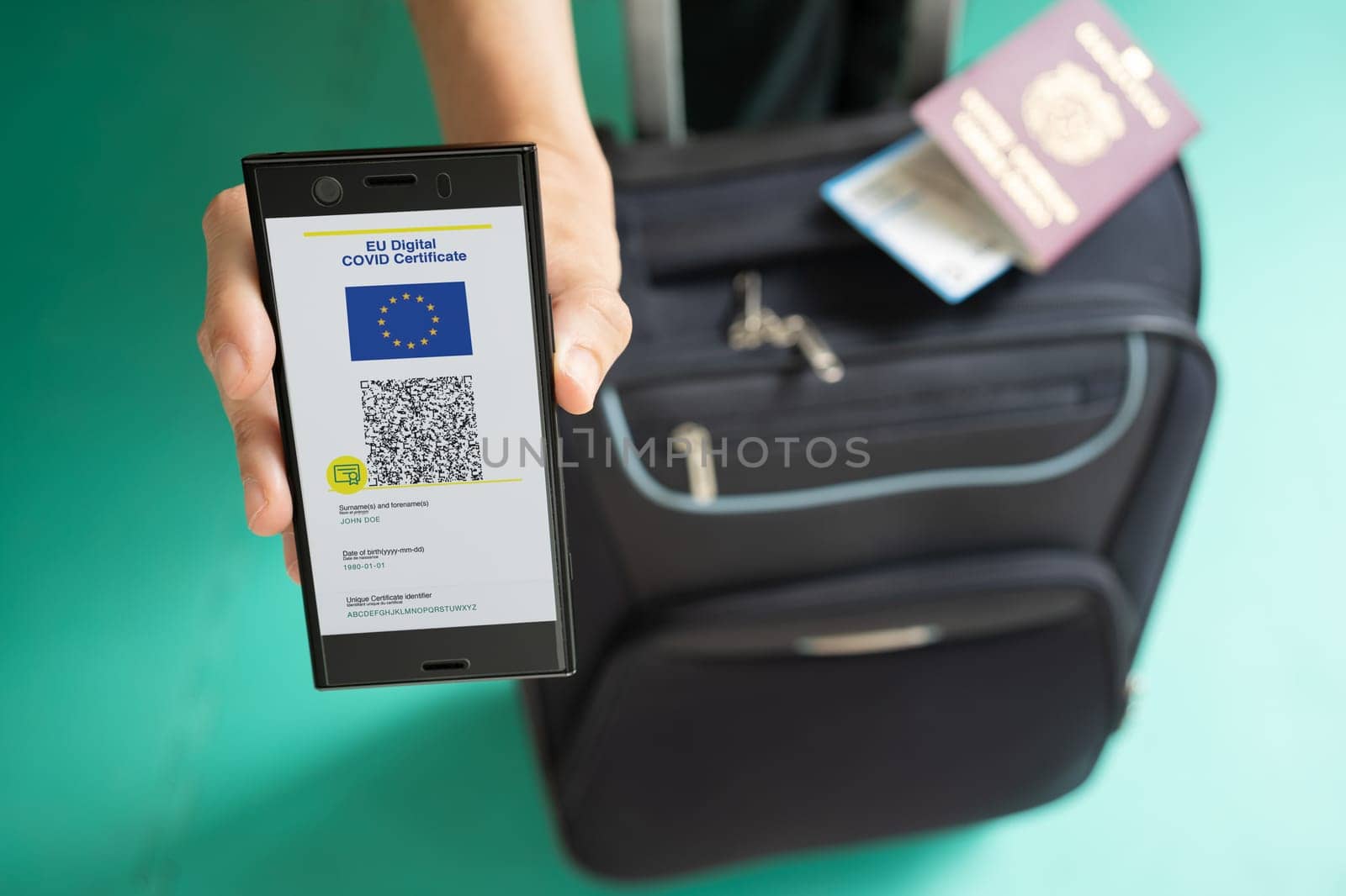Woman showing on smartphone EU Digital Covid Certificate with quad code. With passport, boarding pass and baggage.