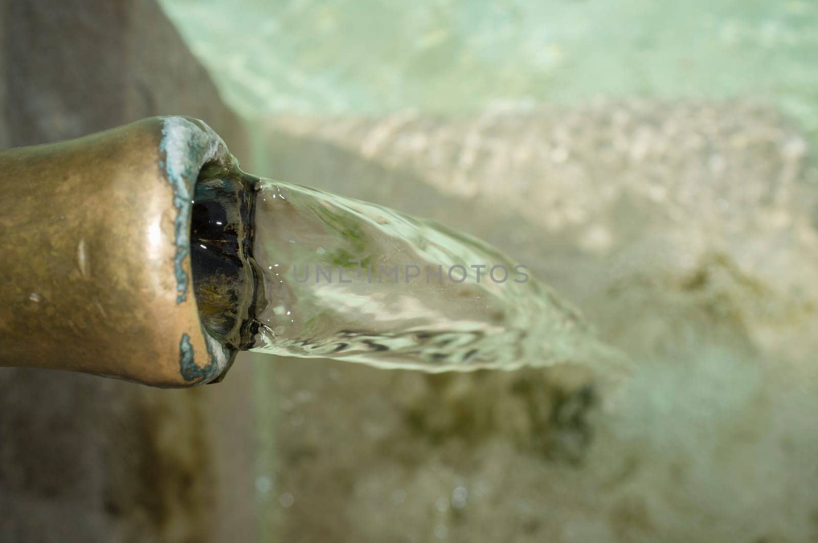 Water permanently flowing from a pipe of a public fountain. Concept of drinking water supply in ancient times