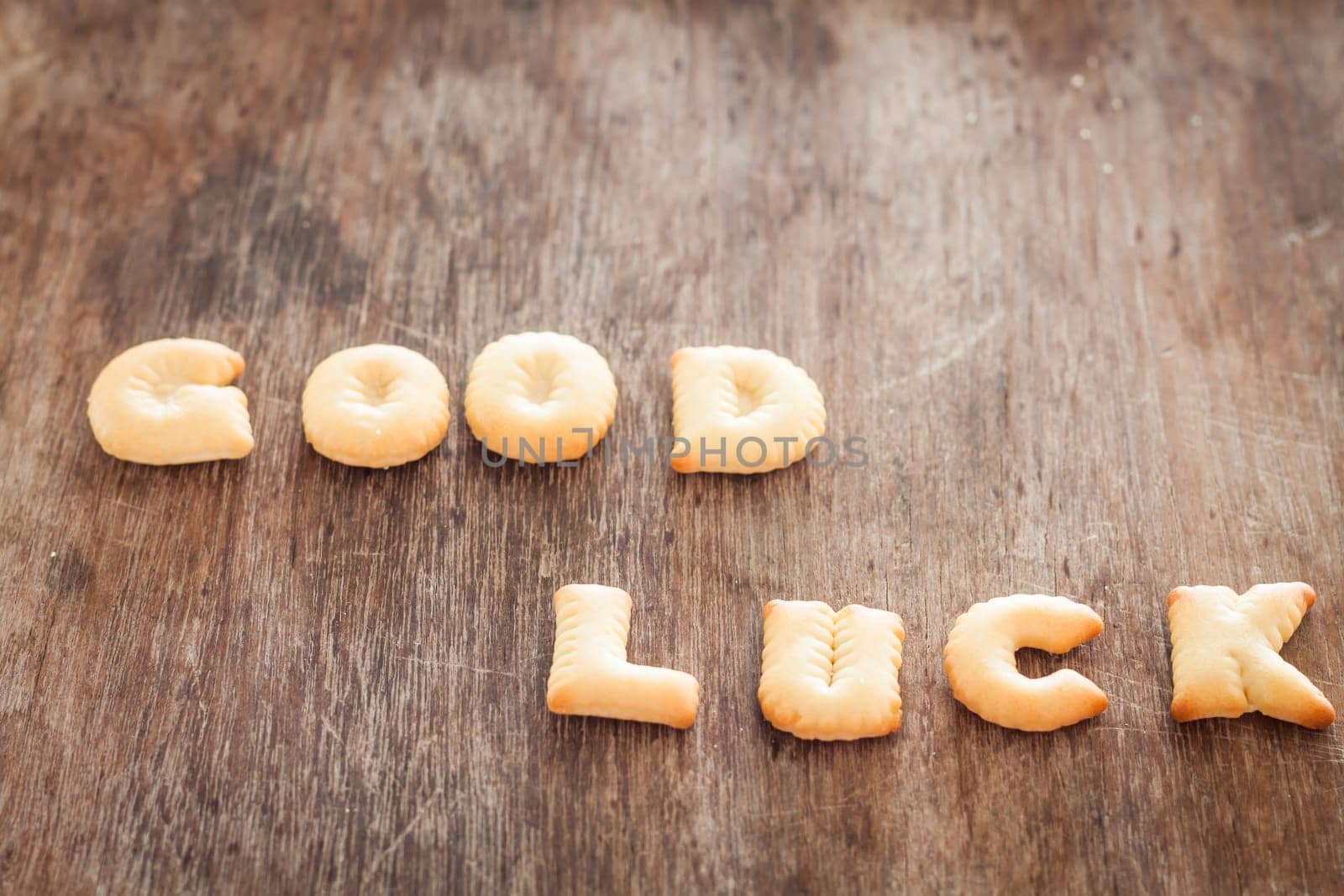 Good luck alphabet biscuit on wooden table, stock photo