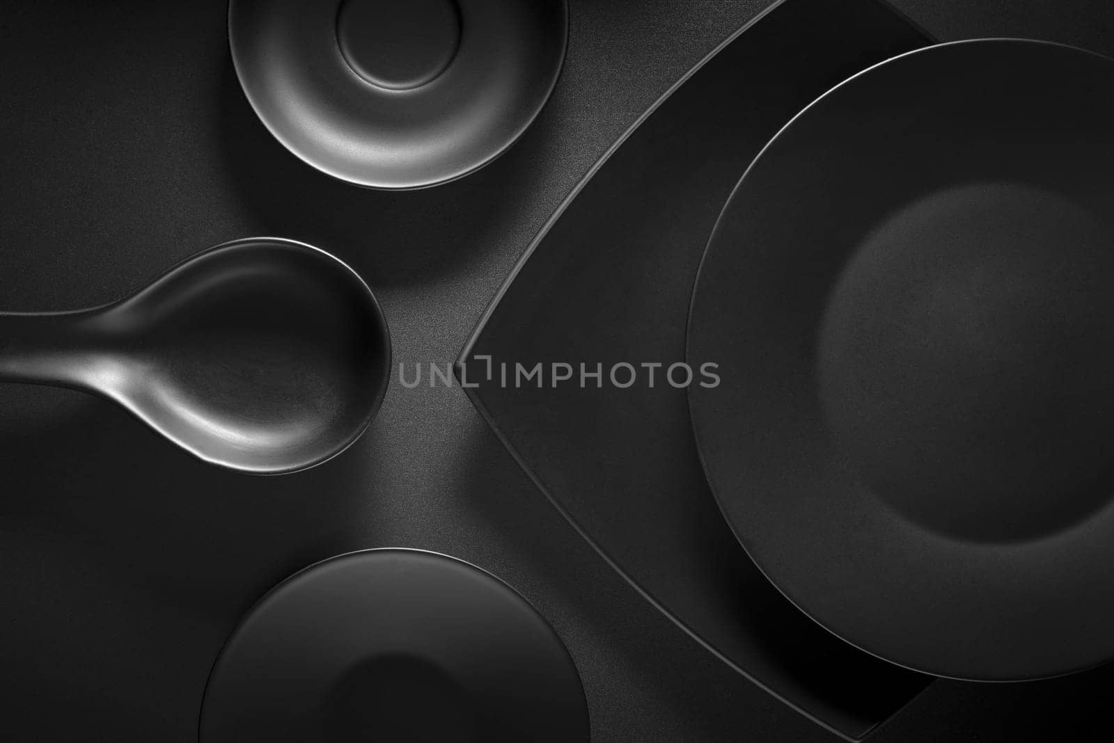 Top view of black empty plates on dark grey background.
