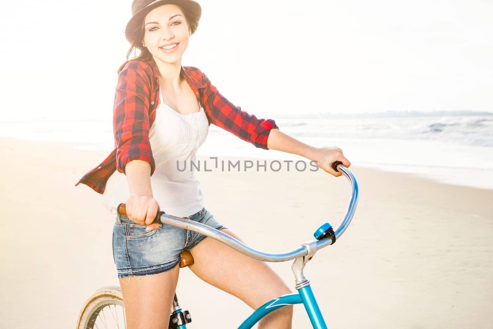 An attractive young woman riding her bicycle on the beach