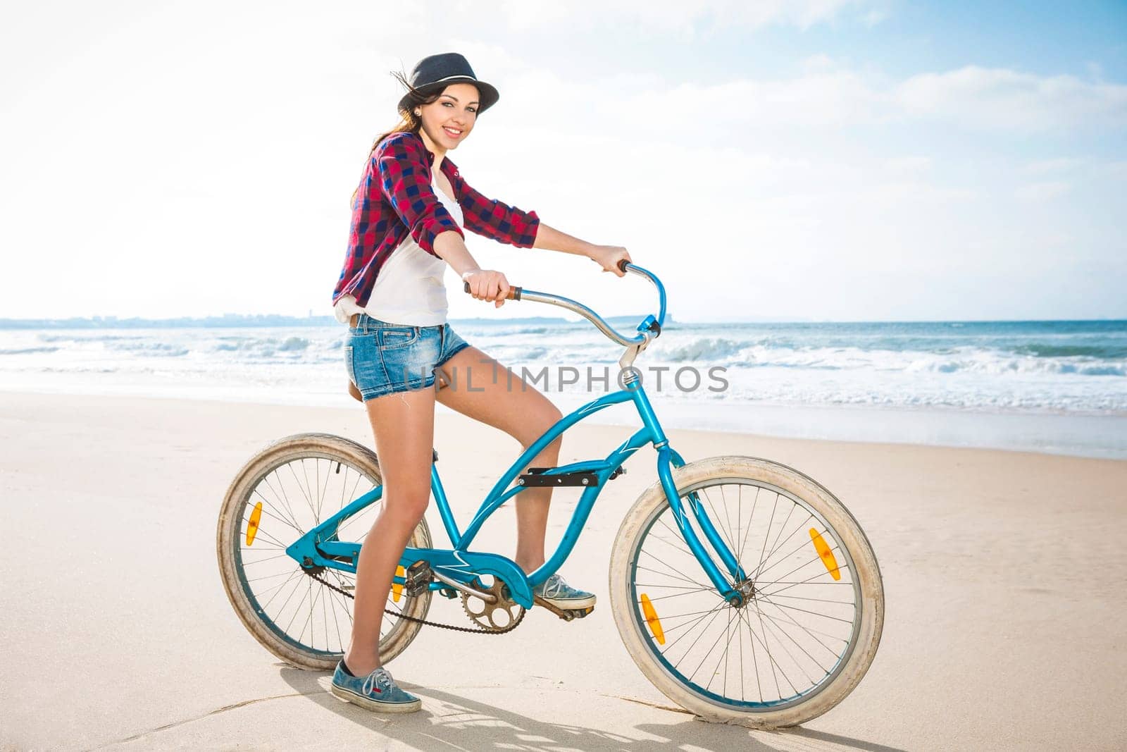 An attractive young woman riding her bicycle on the beach