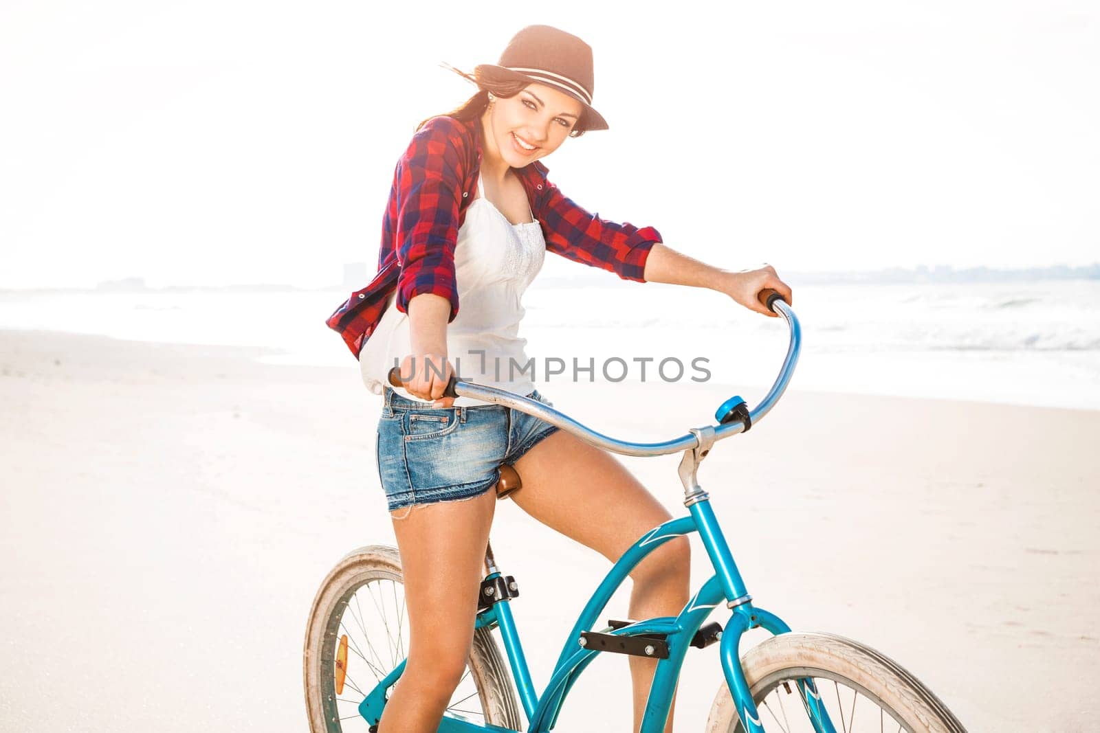 An attractive young woman riding her bicycle on the beach