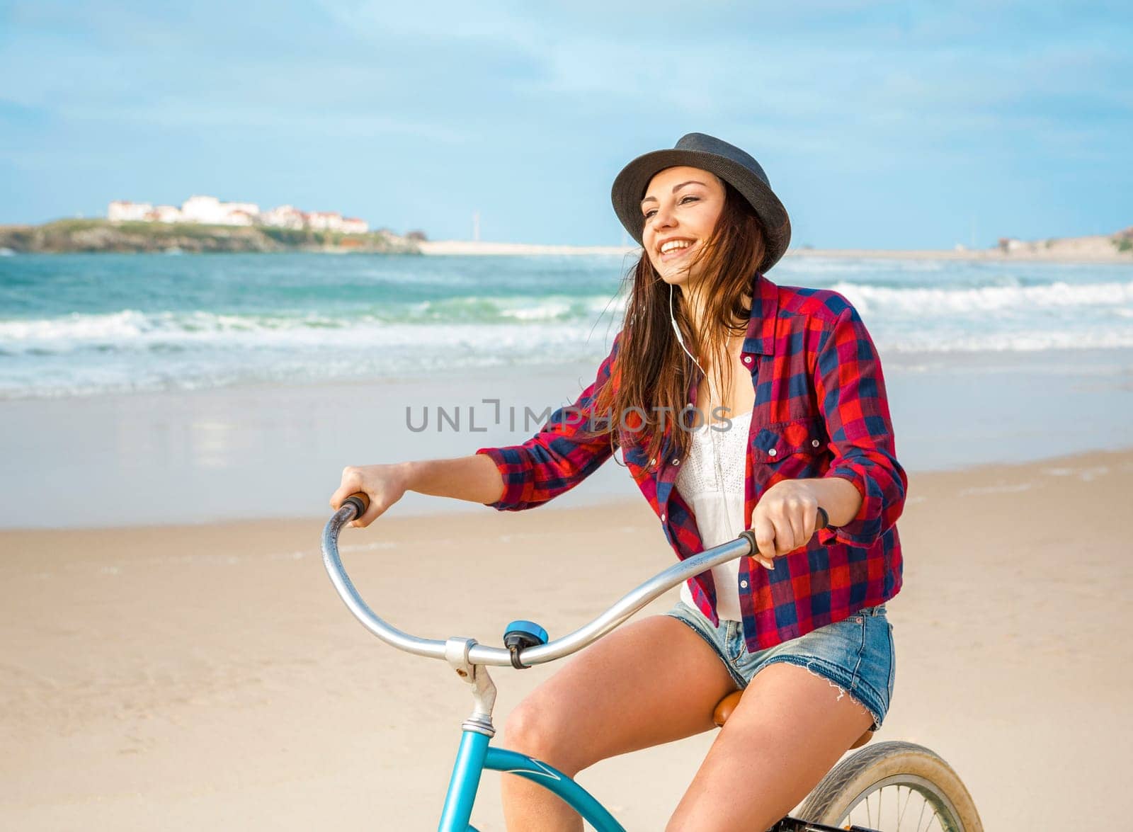 An attractive young woman riding her bicycle on the beach