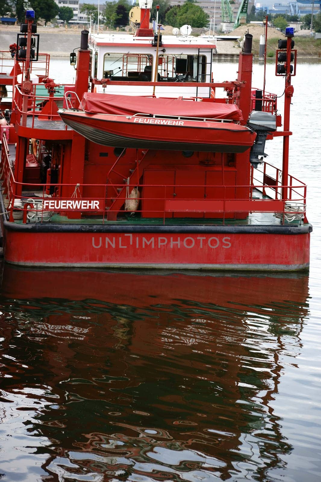 A firefighting boat of the fire brigade anchors at the pier of a river.