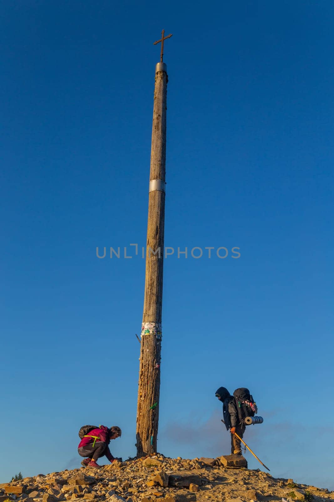 Foncebadon, Spain - 20 August 2022: Pilgrims next to the iron cross called cruz de Hierro along the way of St. James