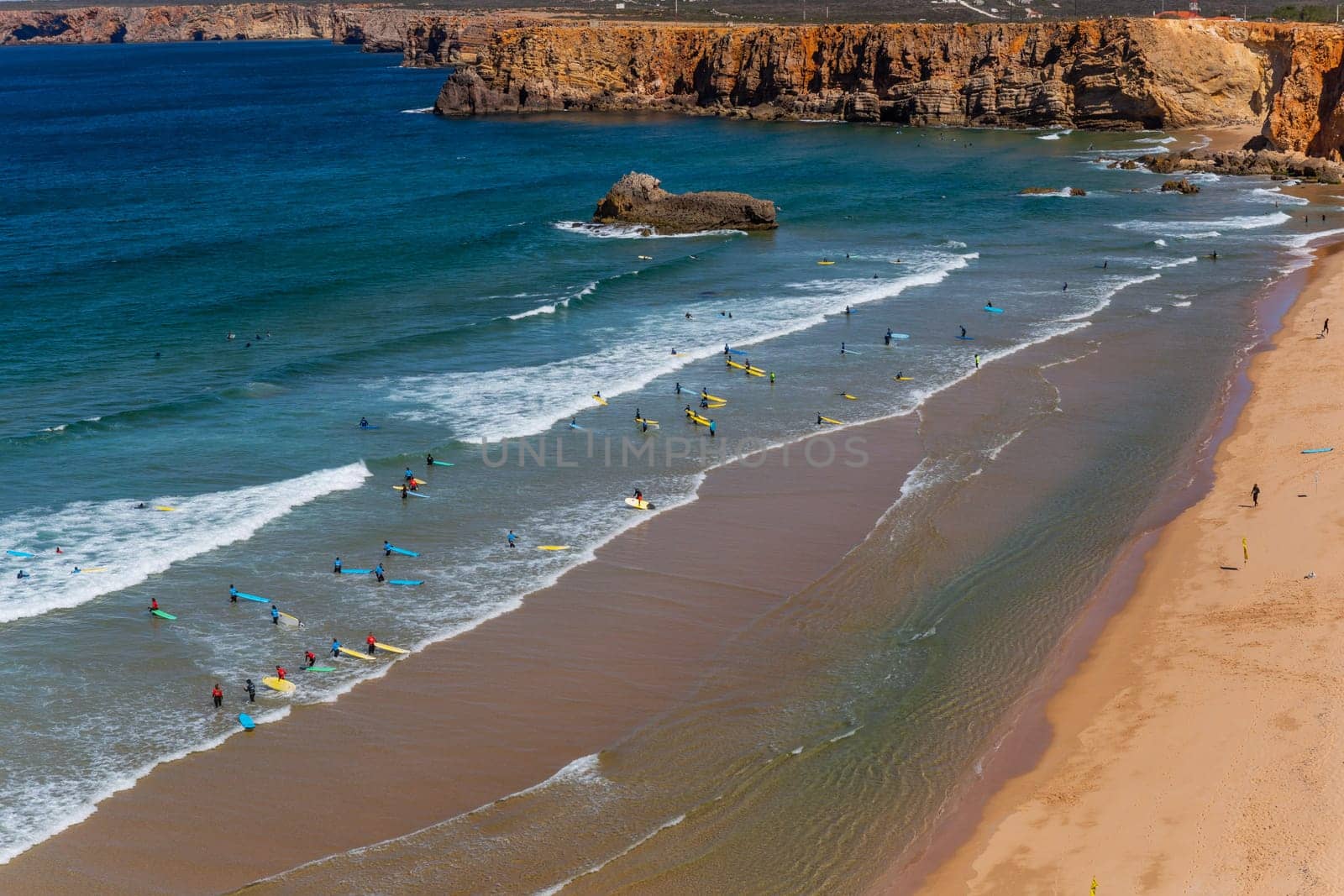 Sagres, Portugal - August 25, 2022: View of surfers on sandy beach near Sagres village in Algarve, Portugal