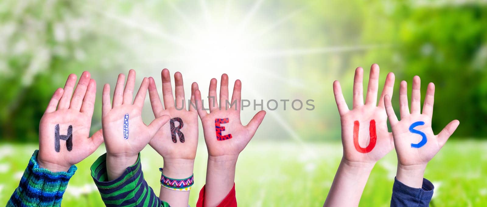 Children Hands Building Colorful English Word Hire Us. Sunny Green Grass Meadow As Background.