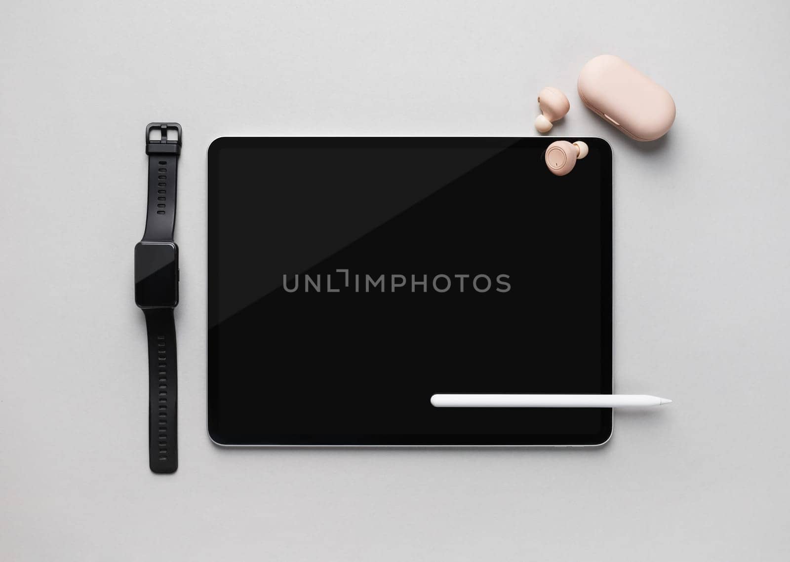 Modern digital tablet, stylus pen, smartwatch and headphones on gray paper background. Responsive design mockup. Top view. Flat lay.