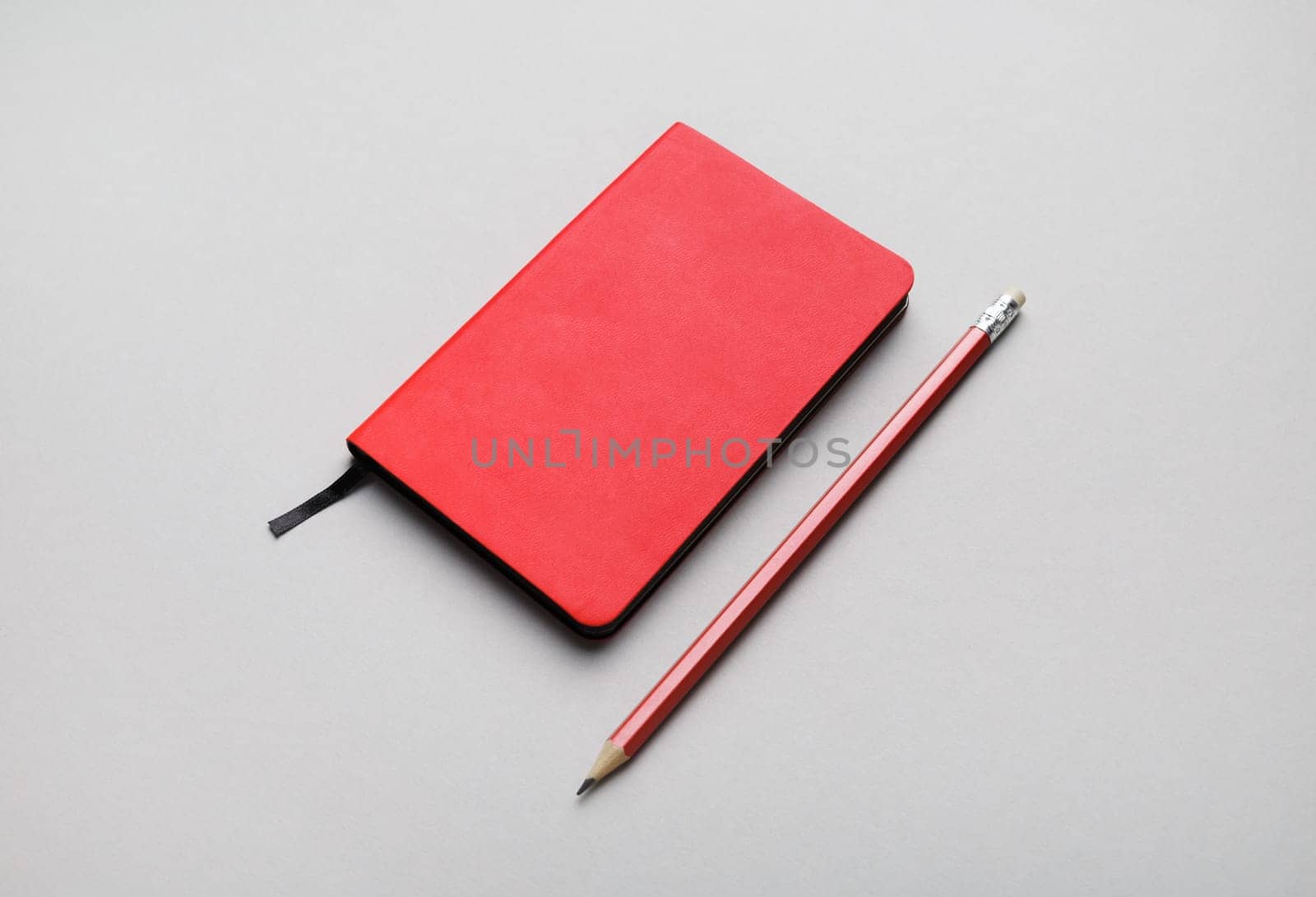 Blank red notepad and pencil on gray paper background. Blank branding template.