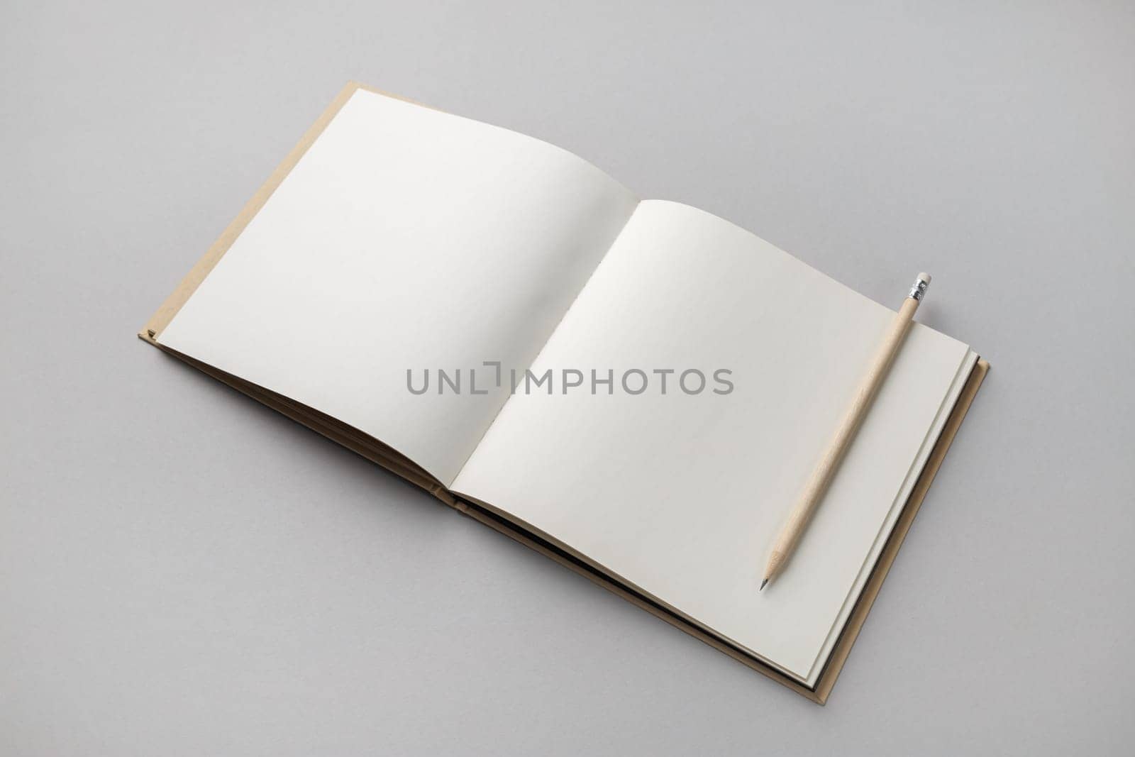 Blank open sketchbook and pencil on gray paper background. Responsive design template.