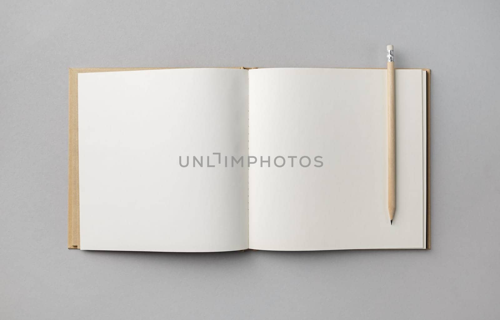 Blank open book or brochure and pencil on gray paper background. Responsive design mockup. Flat lay.