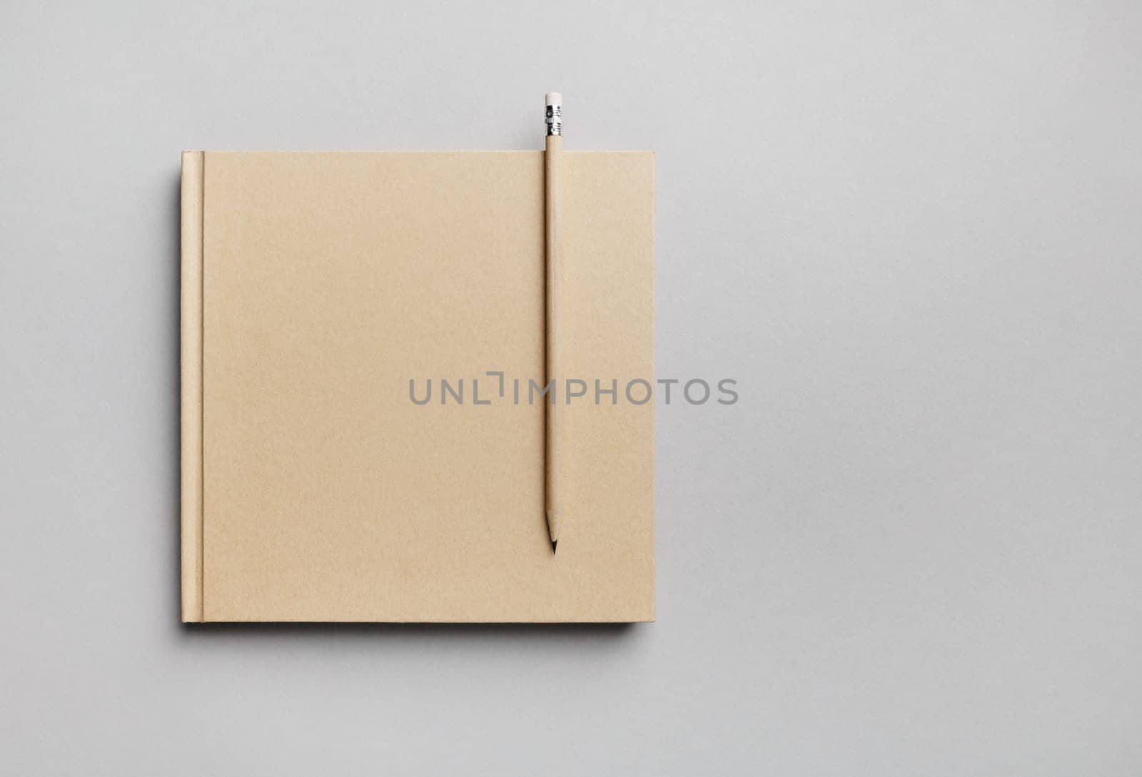 Blank closed book and pencil on gray paper background. Responsive design template. Copy space for text. Flat lay.