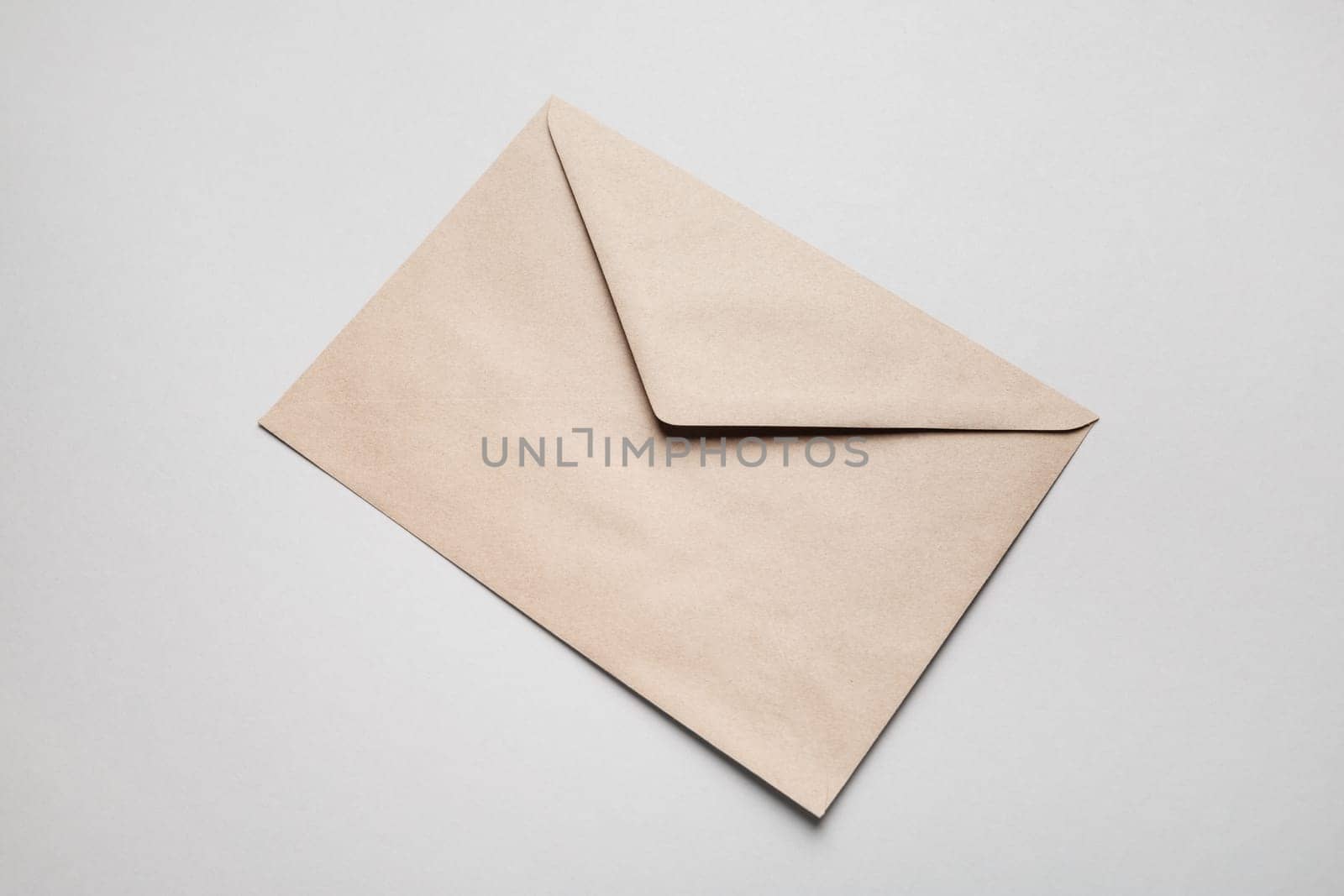 Photo of blank kraft paper envelope on gray paper background.