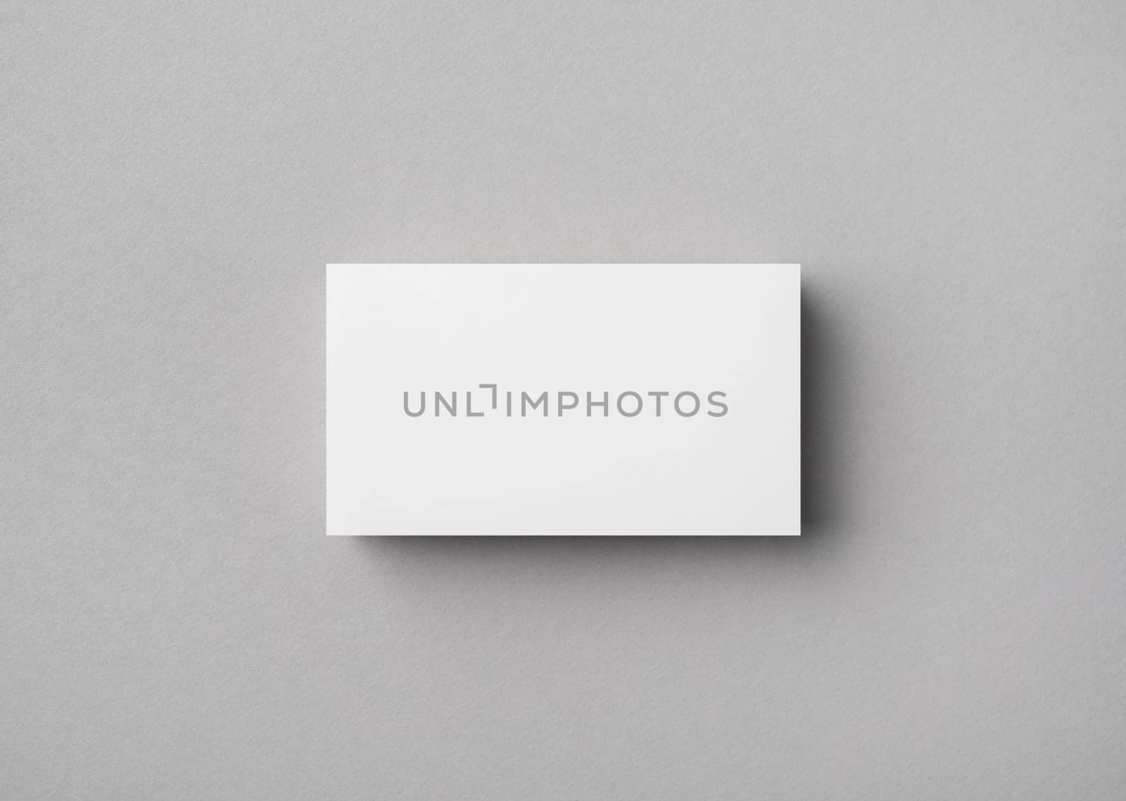 Blank business card on gray paper background. Mock-up for branding identity. Flat lay.