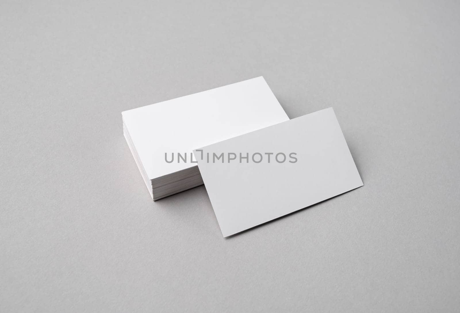 Blank white business cards on gray paper background. Mock-up for branding identity.