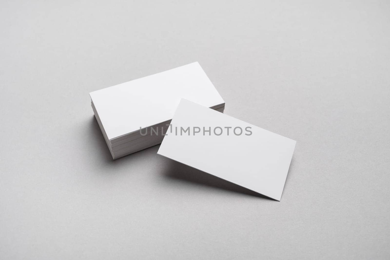 Blank white business cards on gray paper background. Mockup for ID.