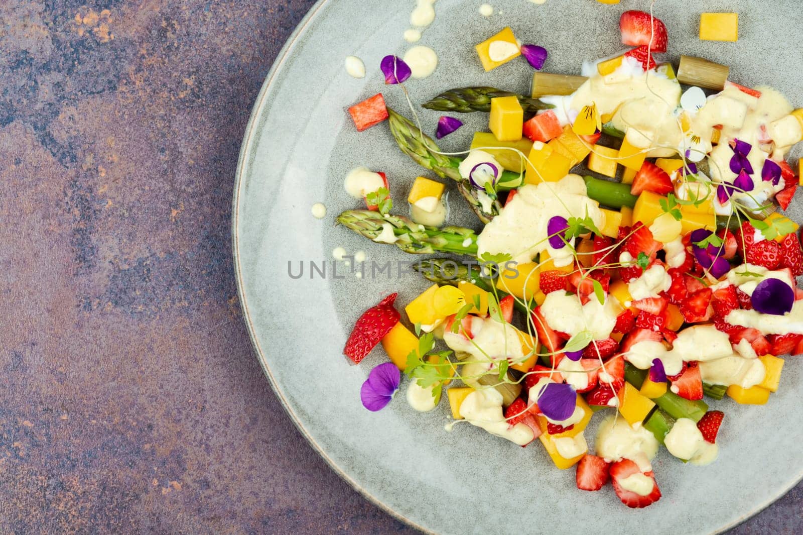 Light spring salad of berries, green asparagus, mango and yogurt. Copy space. Banner.