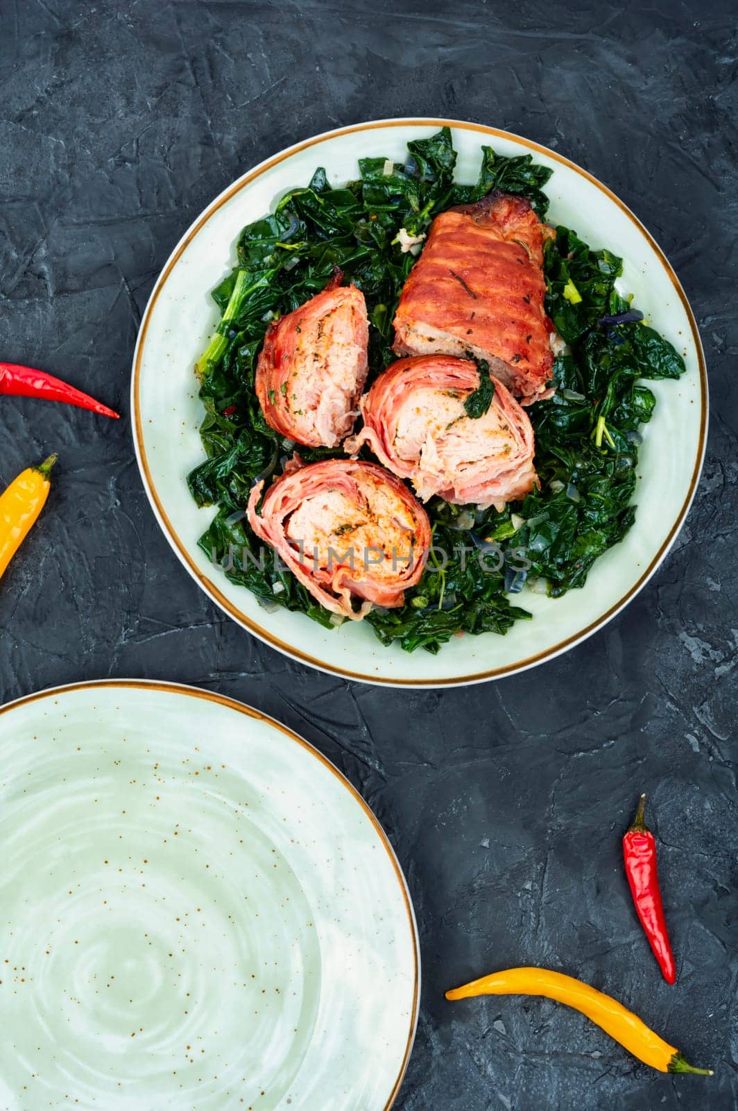 Sliced Baked chicken meat breast roll with fried spinach garnish.
