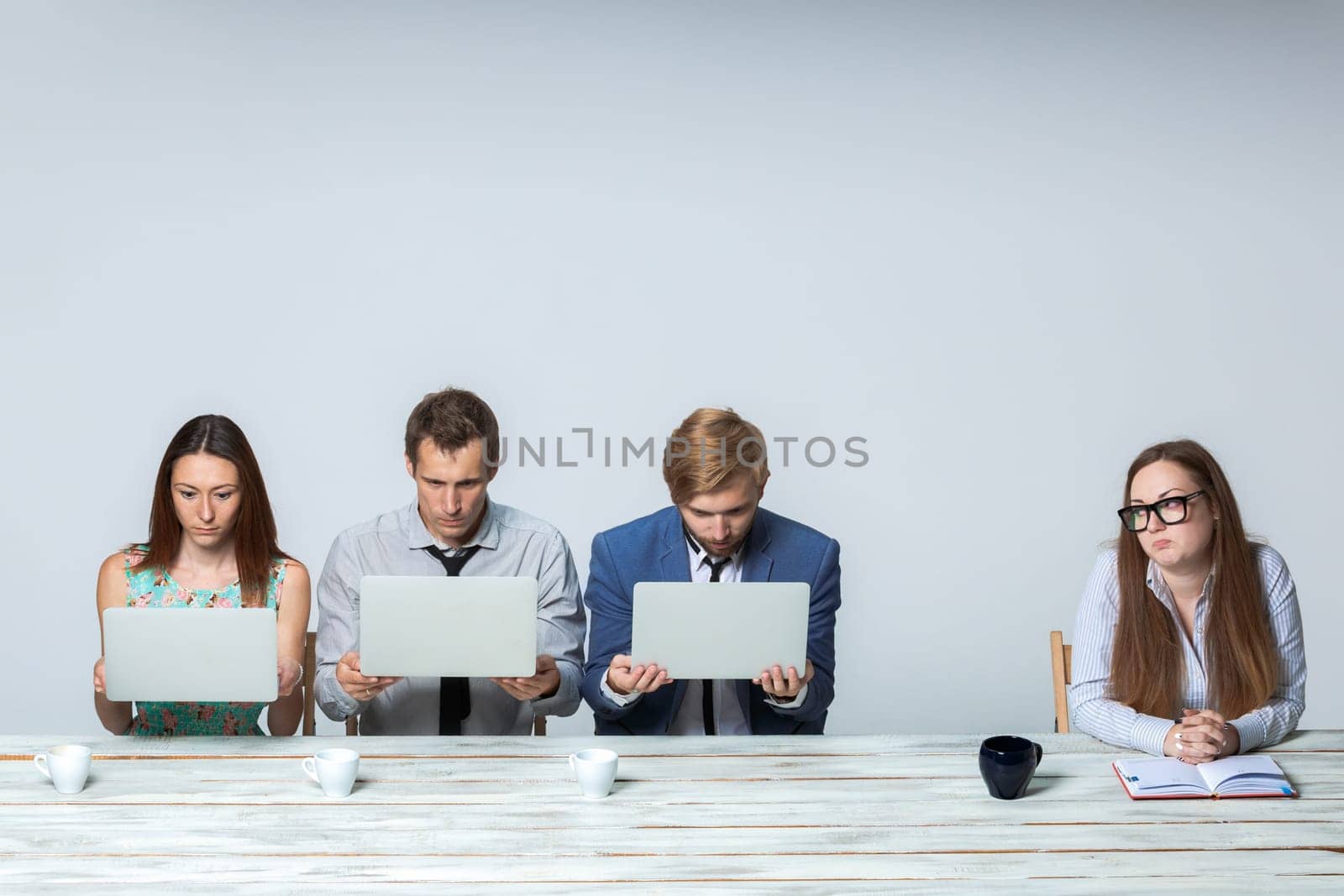 Business team working together at office on light gray background. all working on laptops. boss watching  the process. copyspace image