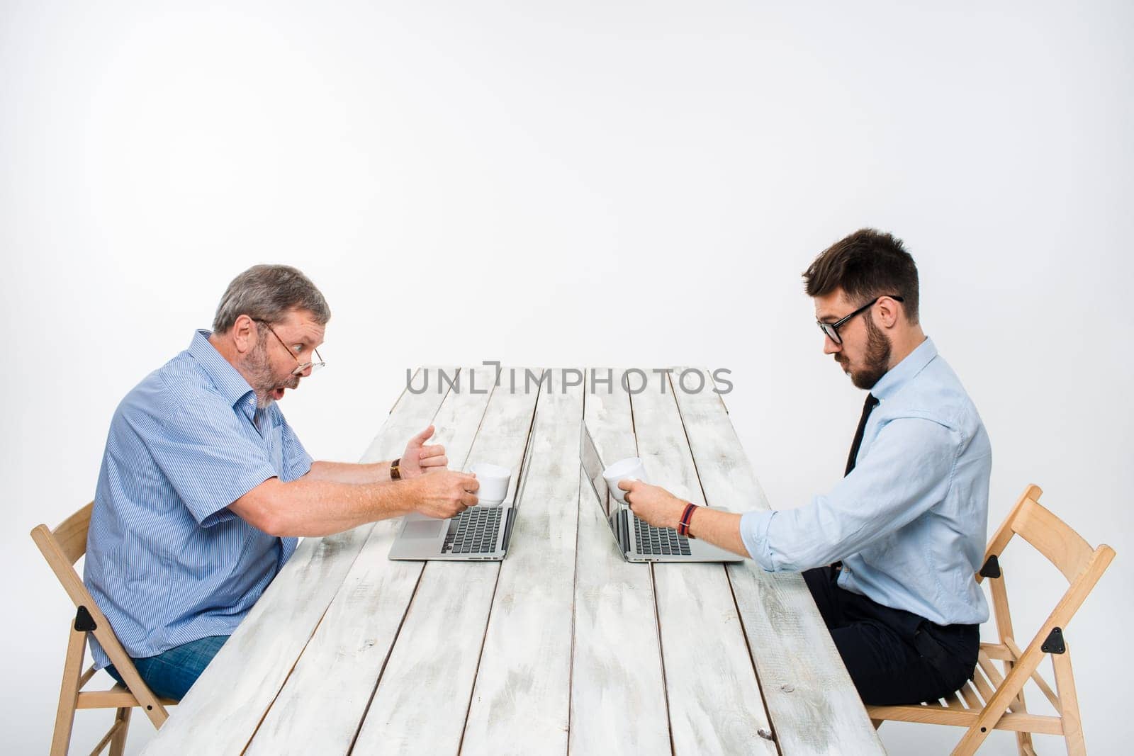 two colleagues working on project together on light gray background. They drinking coffee. happy man and jealous man. the concept of competition in the business