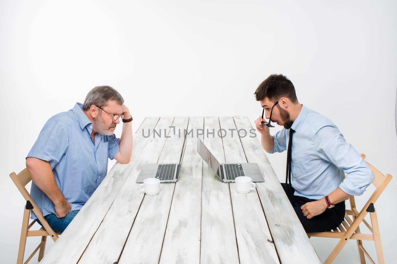 The two colleagues working together at office on light gray background. Both are looking at the computer screens
