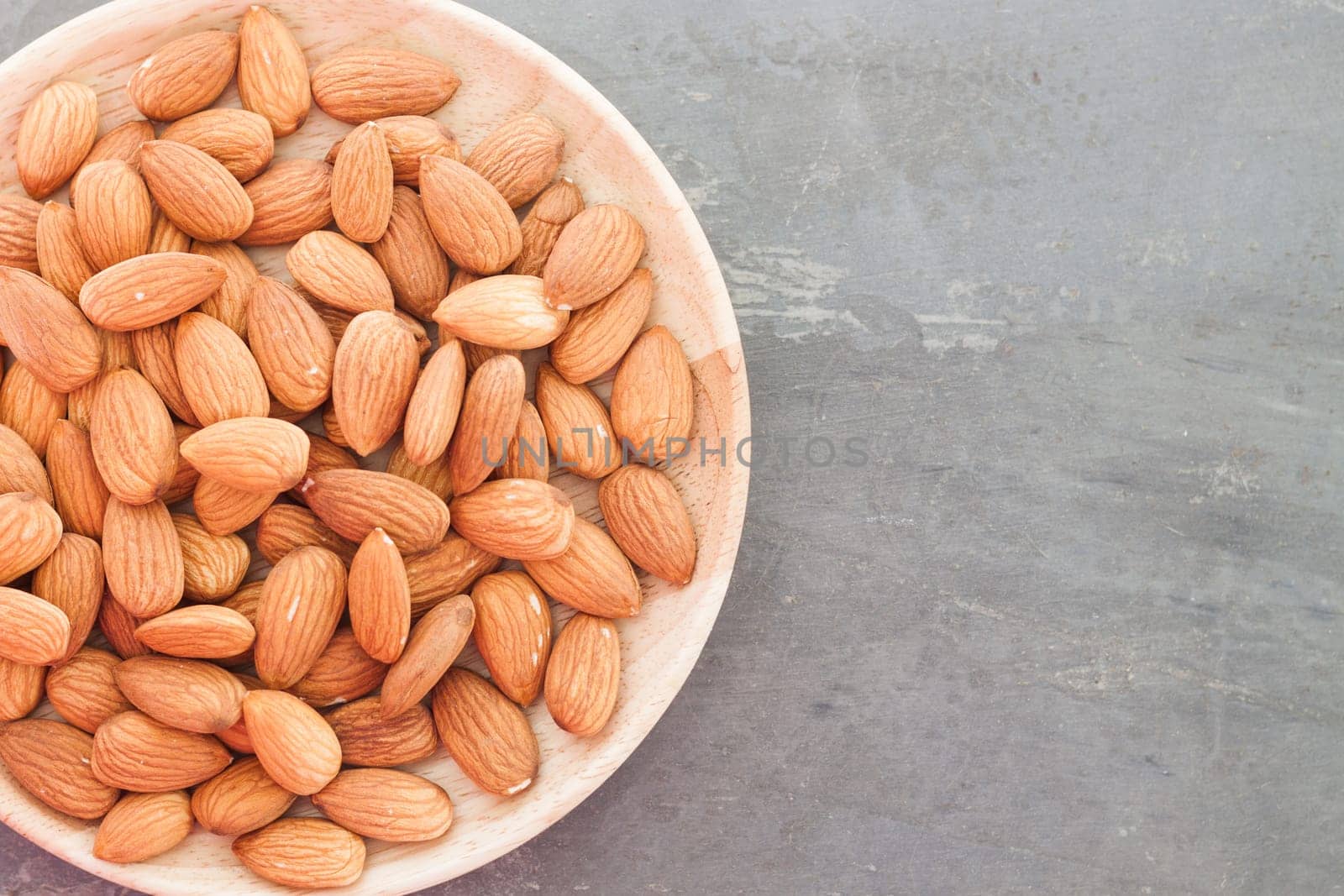 Almond nuts on wooden plate, stock photo