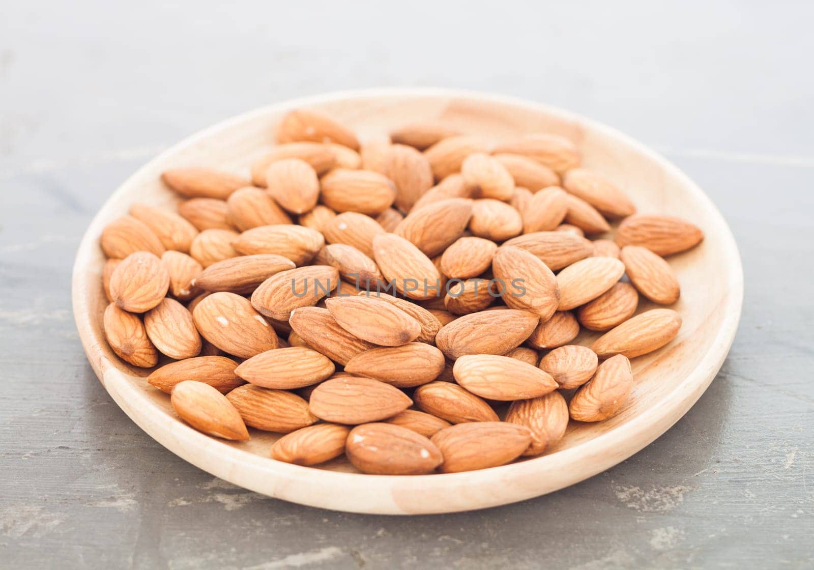 Almond nuts on wooden plate, stock photo
