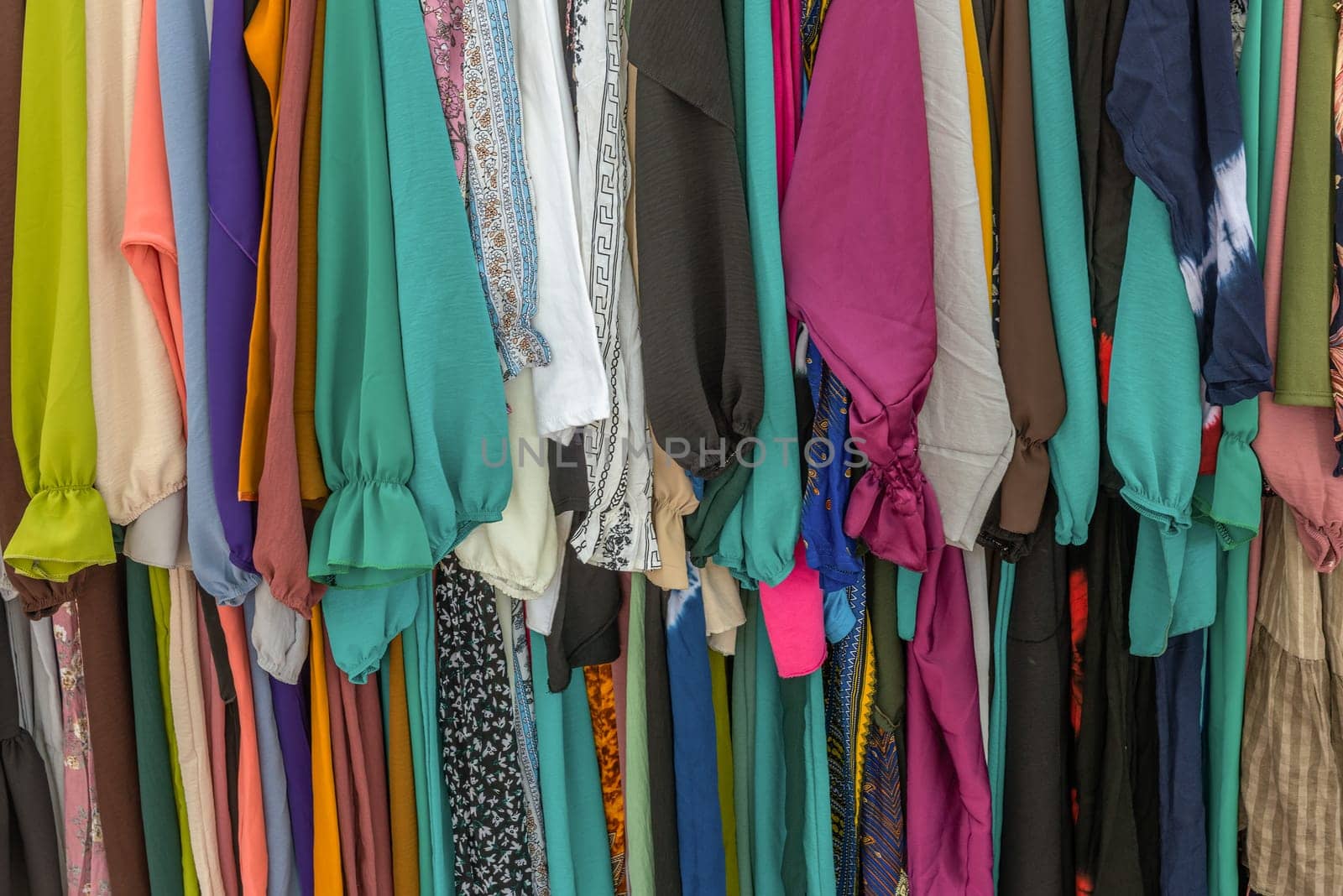 used colorful clothing hanging on a rack at a flea market