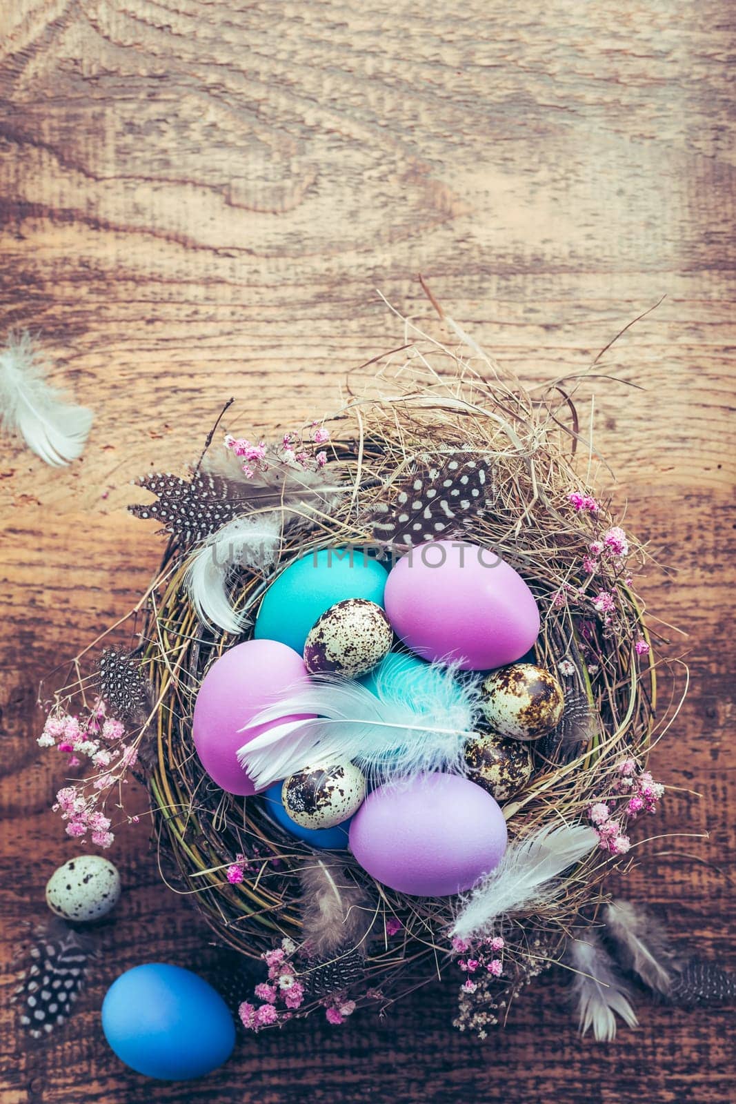 Happy Easter - nest with Easter eggs on wooden background with copy space