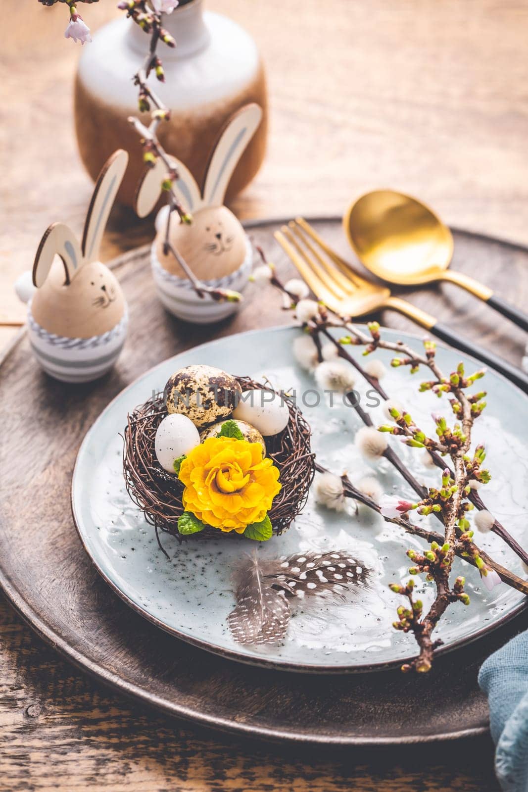 Easter table setting with spring flowers and cutlery on wooden table. Spring Easter Holiday Table