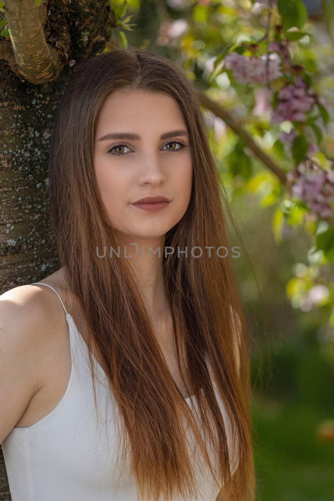 Attractive long hair brunette girl posing on camera outdoors. Vertically.