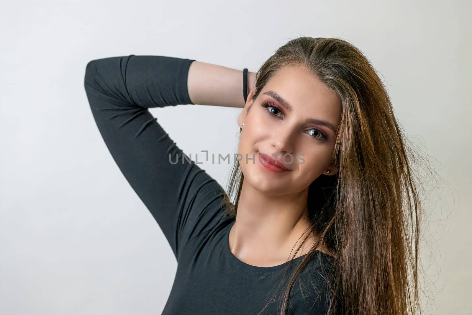 Attractive brunette girl posing with hand in her hand on the light background.