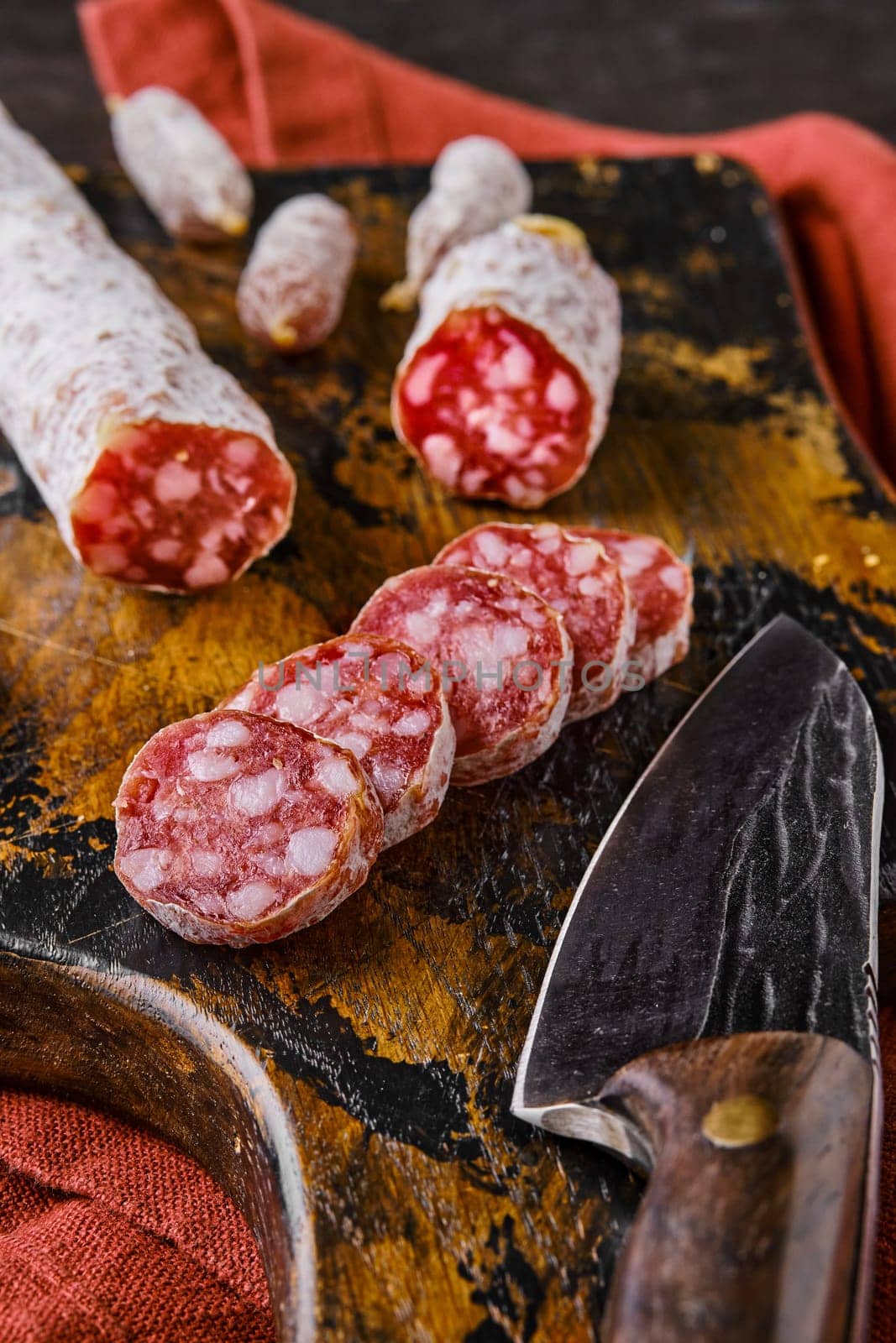 Fermented salami sausages on wooden cutting board cut on slices, closeup view