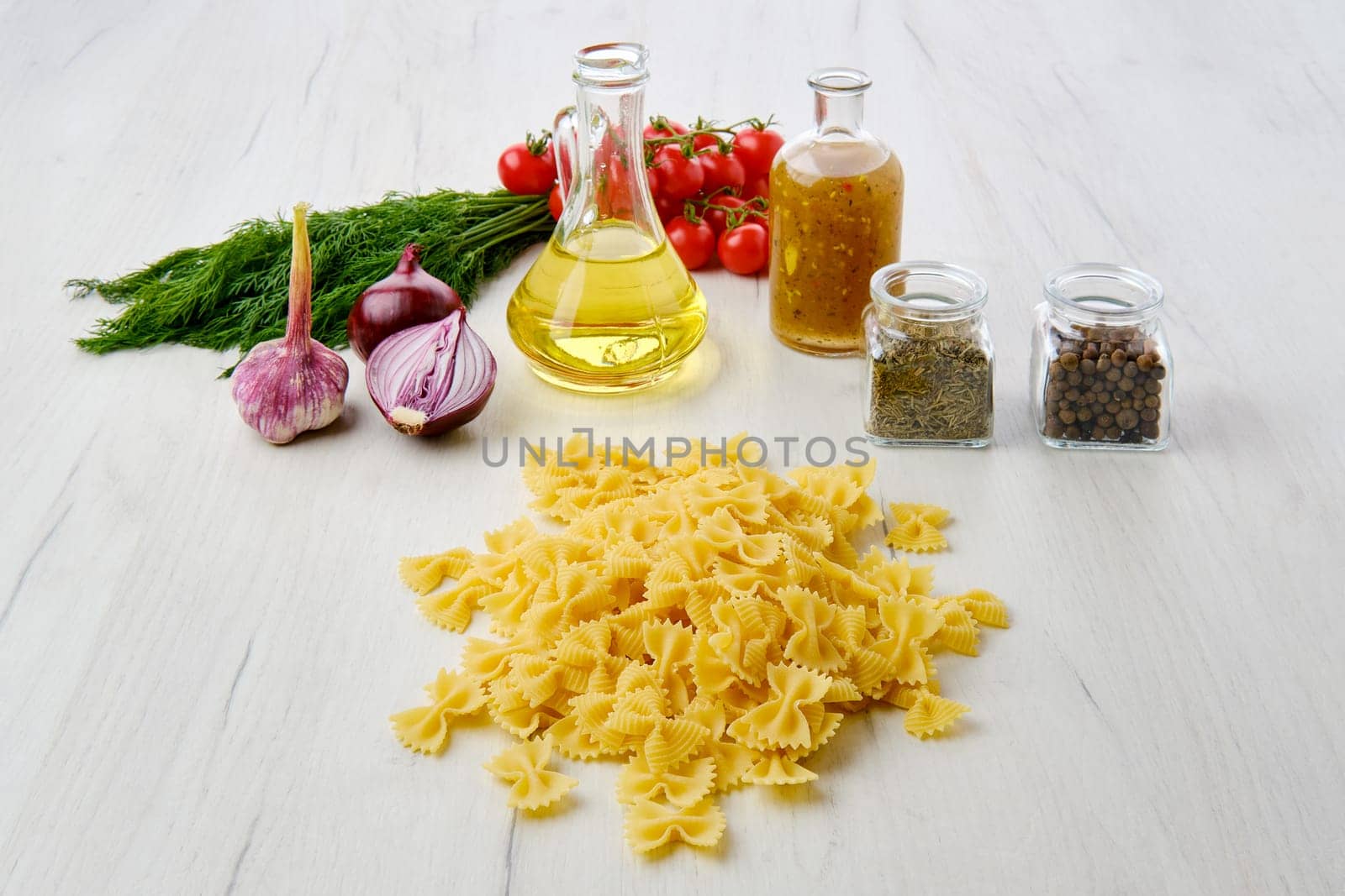 Uncooked pasta farfalline scattered on the table surrounded with ingredients