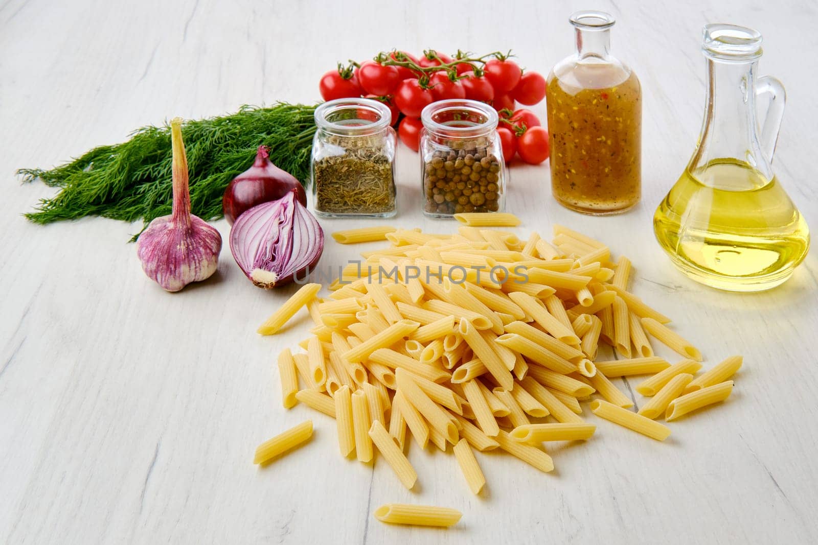 Uncooked pasta farfalline scattered on the table surrounded with ingredients