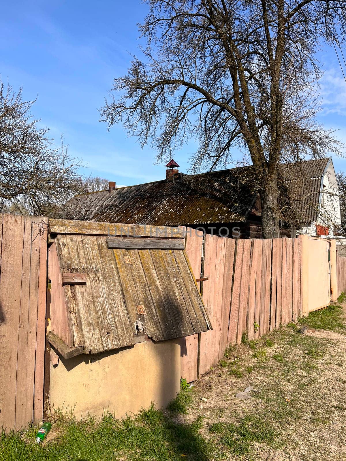 wooden old painted fence near the house in the village and a closed well