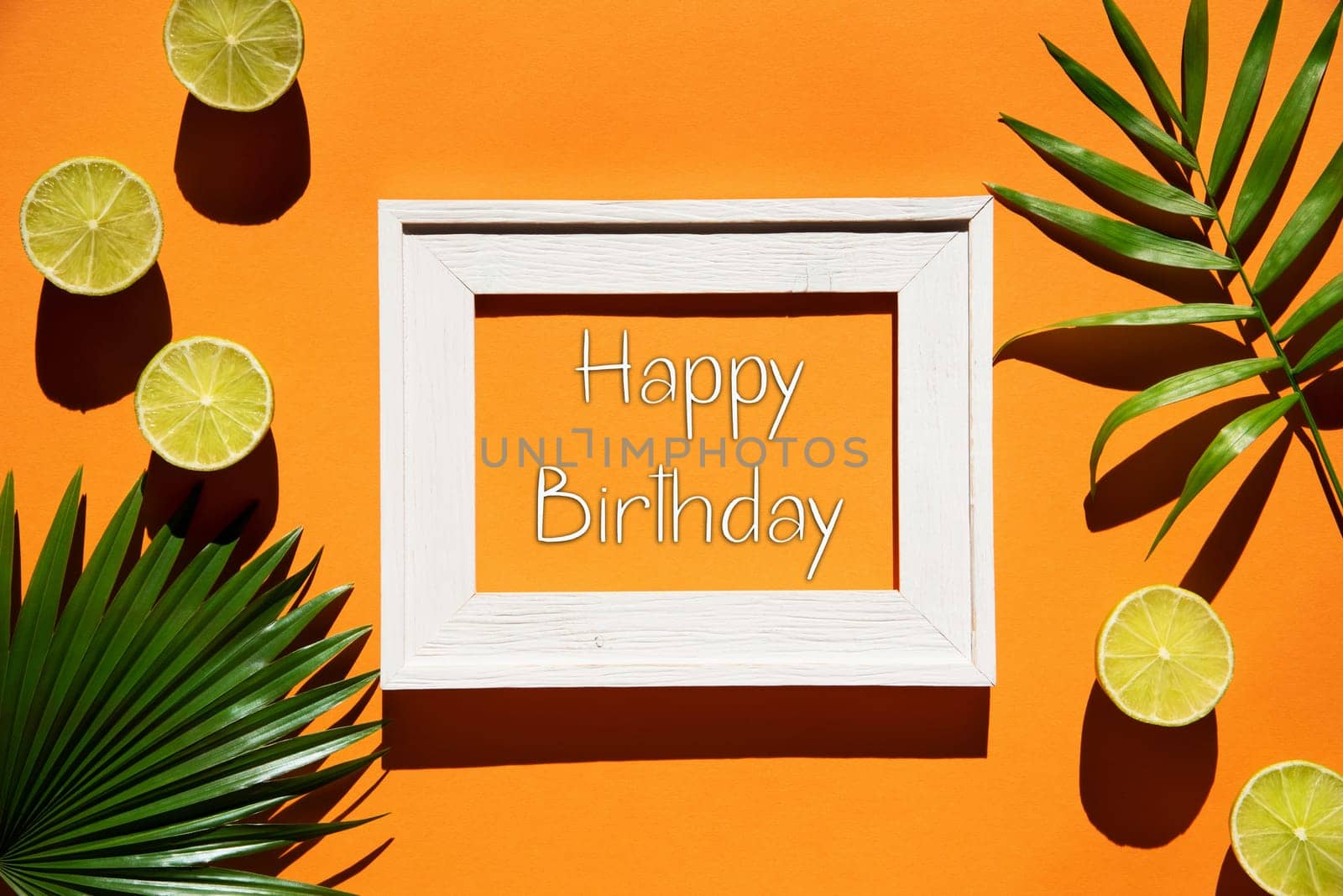Flat Lay With English Text Happy Birthday. Orange Background With Picture Frame And Tropical Lemon And Palm Leaf.
