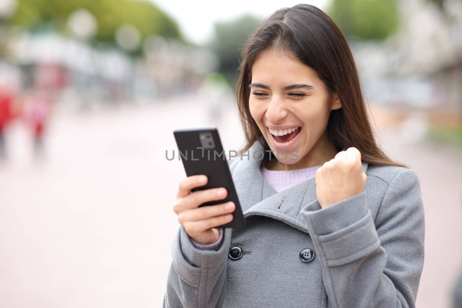 Excited woman checking content on phone in the street
