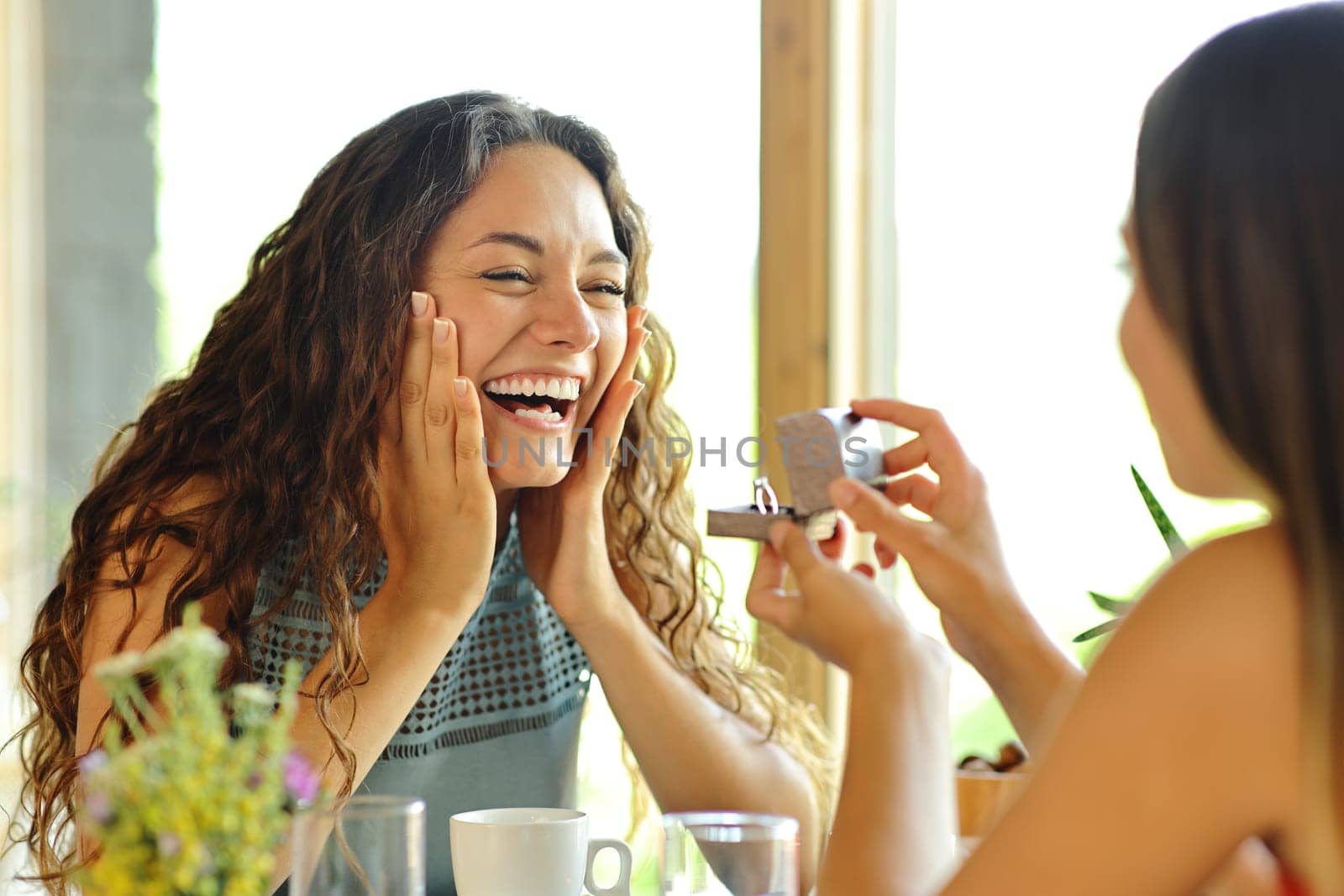 Happy lesbian couple asking for marriage in a restaurant
