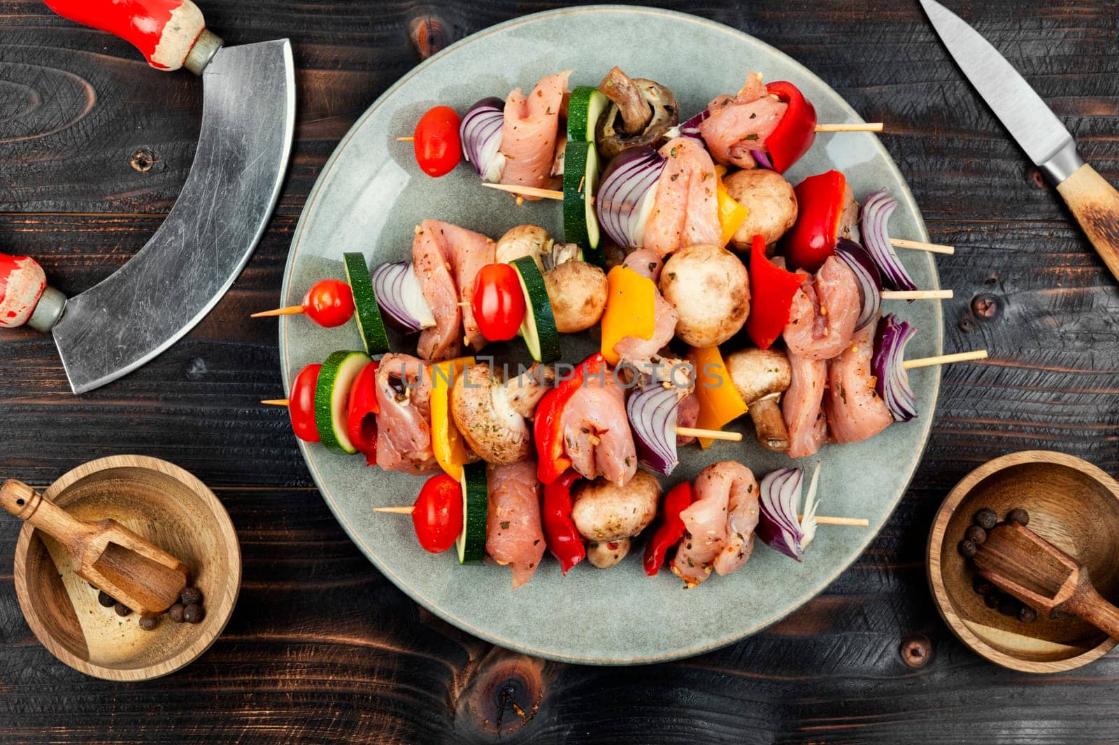 Skewers with pieces of raw meat and vegetables. Barbecue meat spices and herbs.