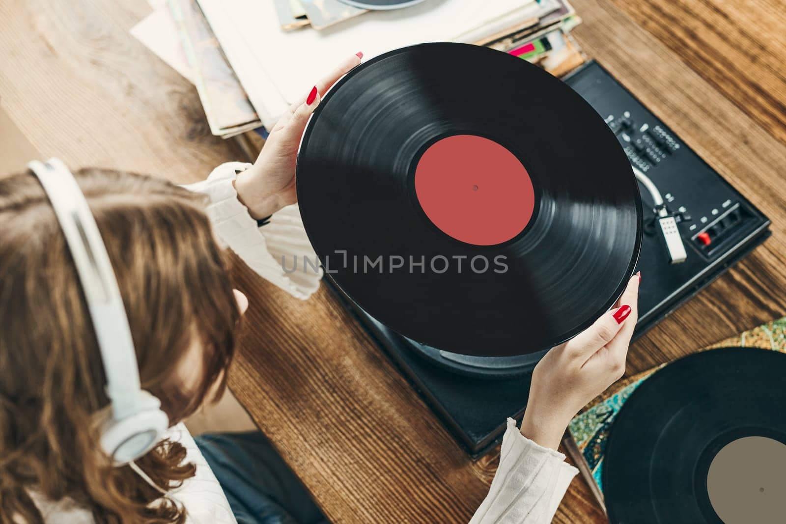 Young woman listening to music from vinyl record player. Playing music on turntable player. Female enjoying music from old record collection at home. Stack of analog vinyl records. Retro and vintage music style. Music Passion and hobby